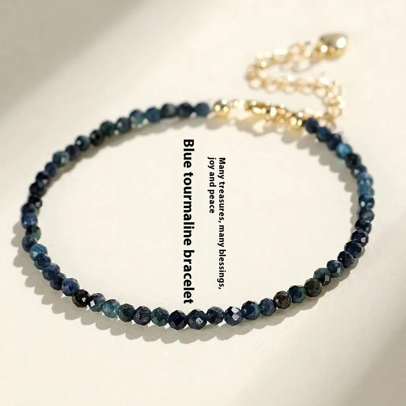 Close-up of a 3mm blue tourmaline cut bead spacer bracelet on a wrist.