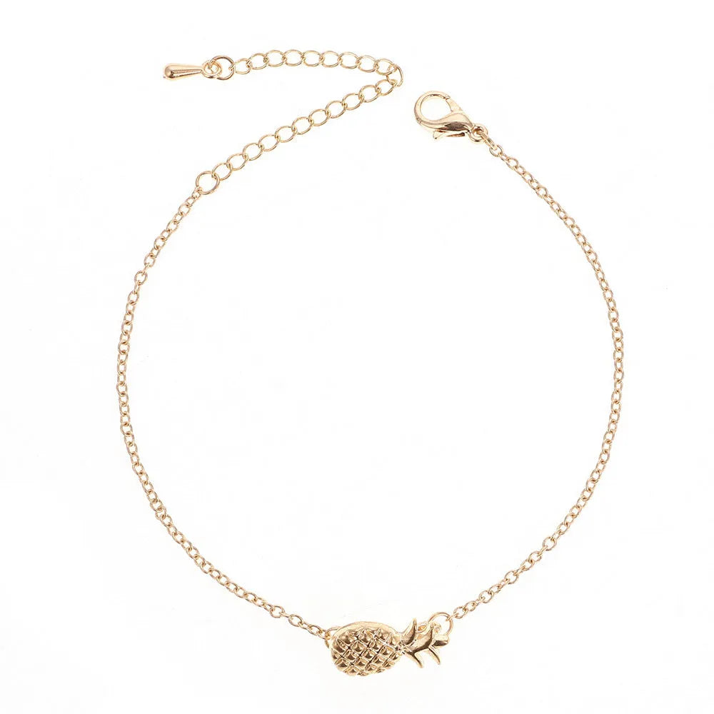 Women's alloy bracelet with a pineapple charm in gold or silver tone on a wrist.