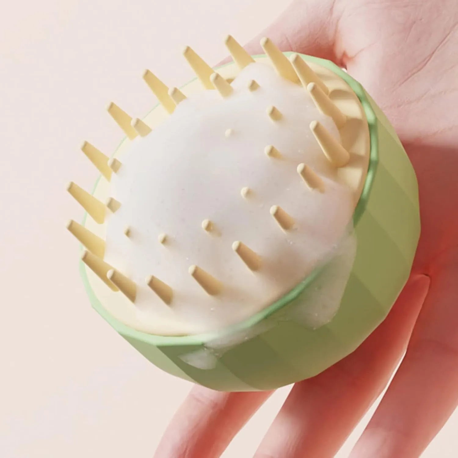 Green pet bath massage brush with drain holes, shown next to a bottle of shampoo for scale.