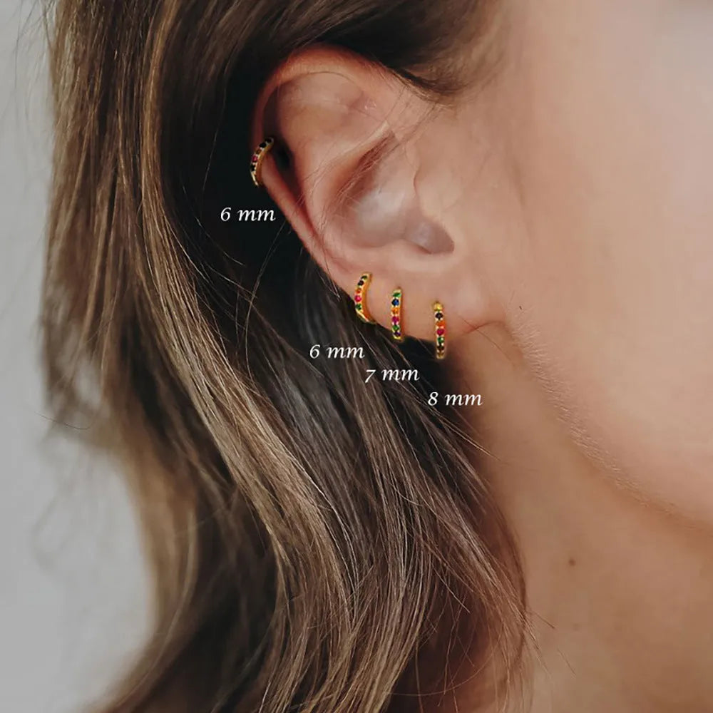 Gold, rose gold, and silver circle stud earrings with a perforated geometric design on a white background.