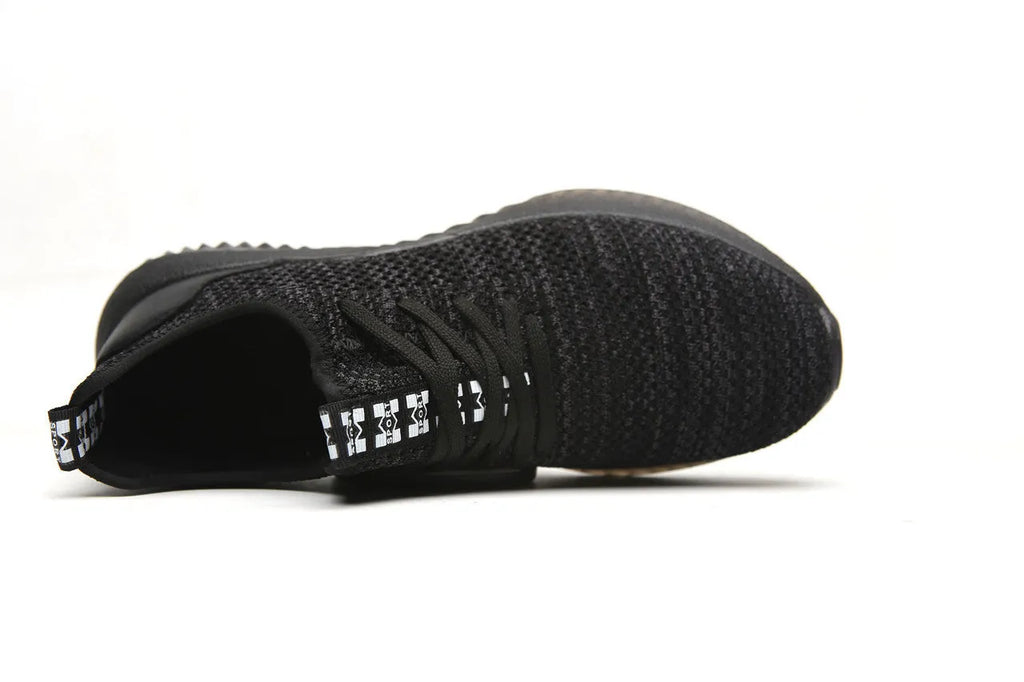 Steel toe cap safety work shoes in black with low-cut design, shown on a work site background.