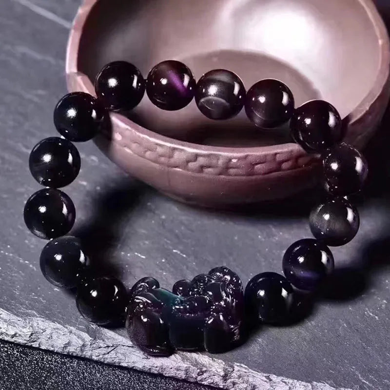 Natural ice colour Eye Obsidian crystal beaded bracelet on a wrist, showing clear spherical beads.
