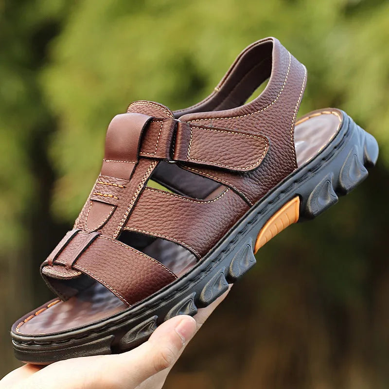 Men's brown cowhide leather sandals with velcro strap and open toe on a beach background