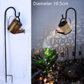 Solar watering can garden lamp with hollow-out iron shower body and 36 warm white LED lights on copper wire, installed in grass