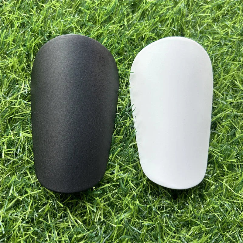 Extra small mini football shin guards measuring 8cm by 5cm in black and white plastic