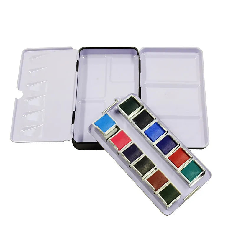 Tinplate metal folding watercolour paint box with colourful printed design, shown open to reveal compartments for solid paint pans.