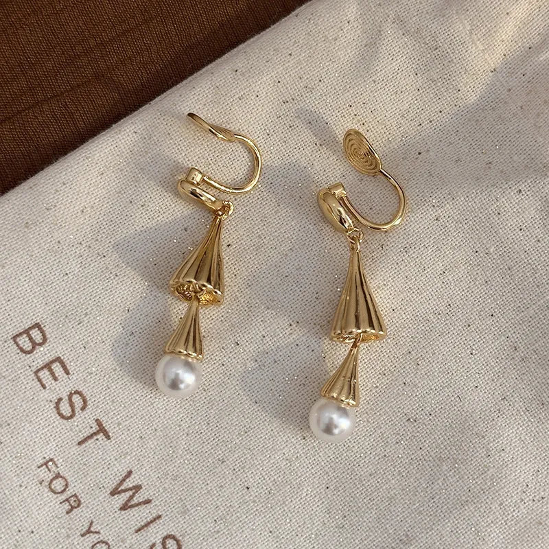 Gold electroplated copper geometric fringe earrings on a woman with long wind chime pearl mosquito coil plate shape close up
