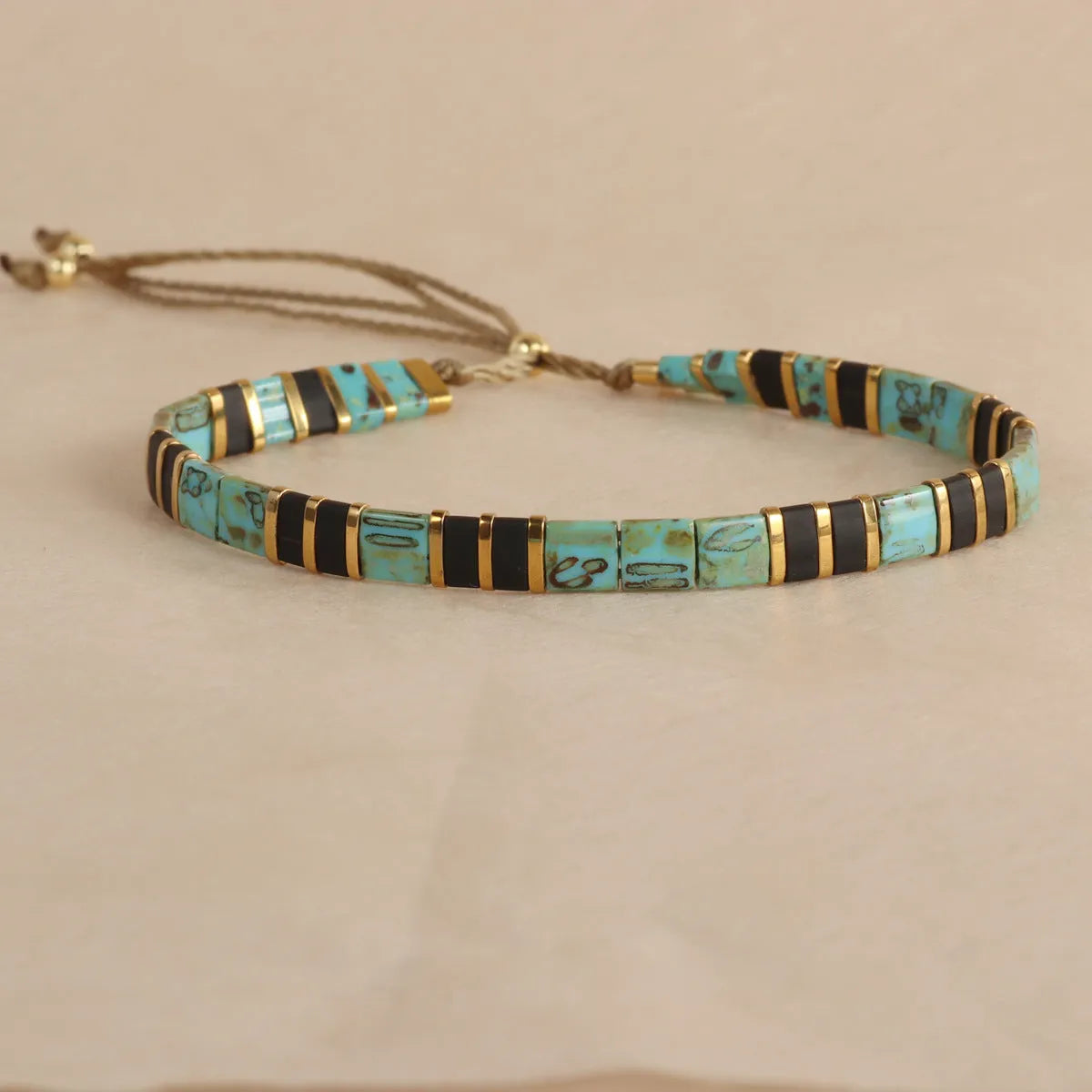 Adjustable geometric beaded bracelet with pull beads in milky white, black, green, blue or red.