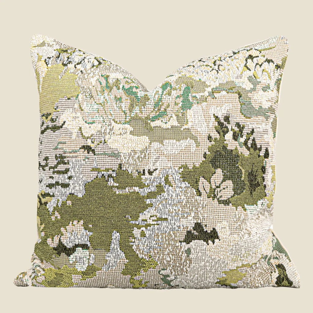 Antique green square pillow with abstract spring flowers pattern on a grey sofa.