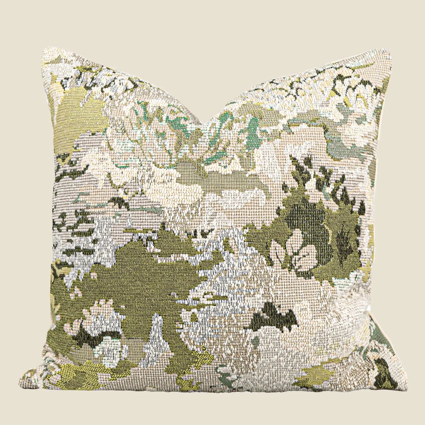 Antique green square pillow with abstract spring flowers pattern on a grey sofa.
