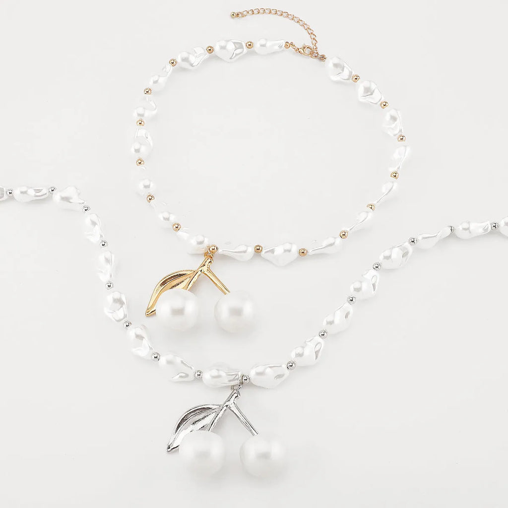 Gold coloured alloy cherry fruit pendant on an adjustable imitation pearl necklace for women.