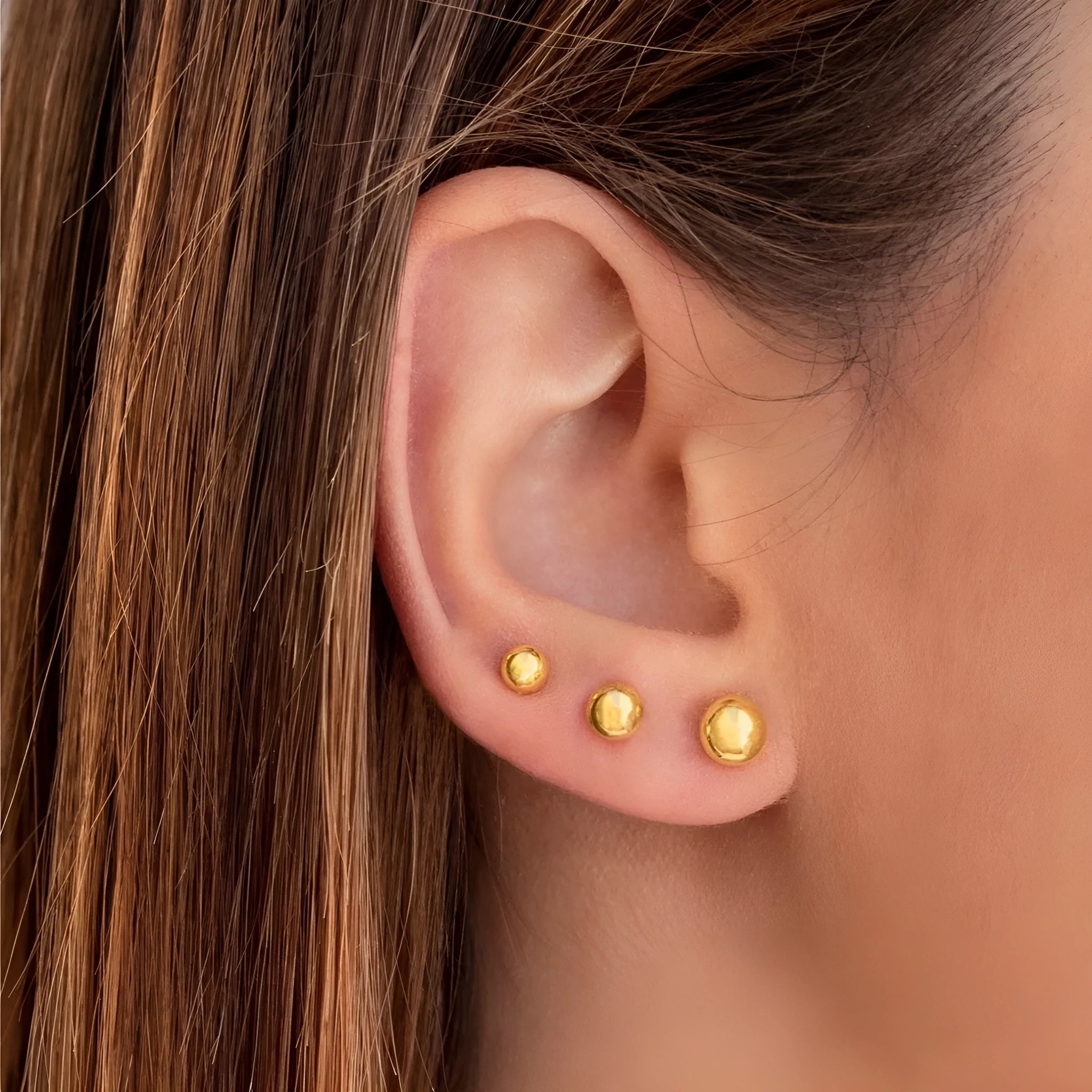 Minimalist round ball stud earrings in gold and silver tones on a plain background.