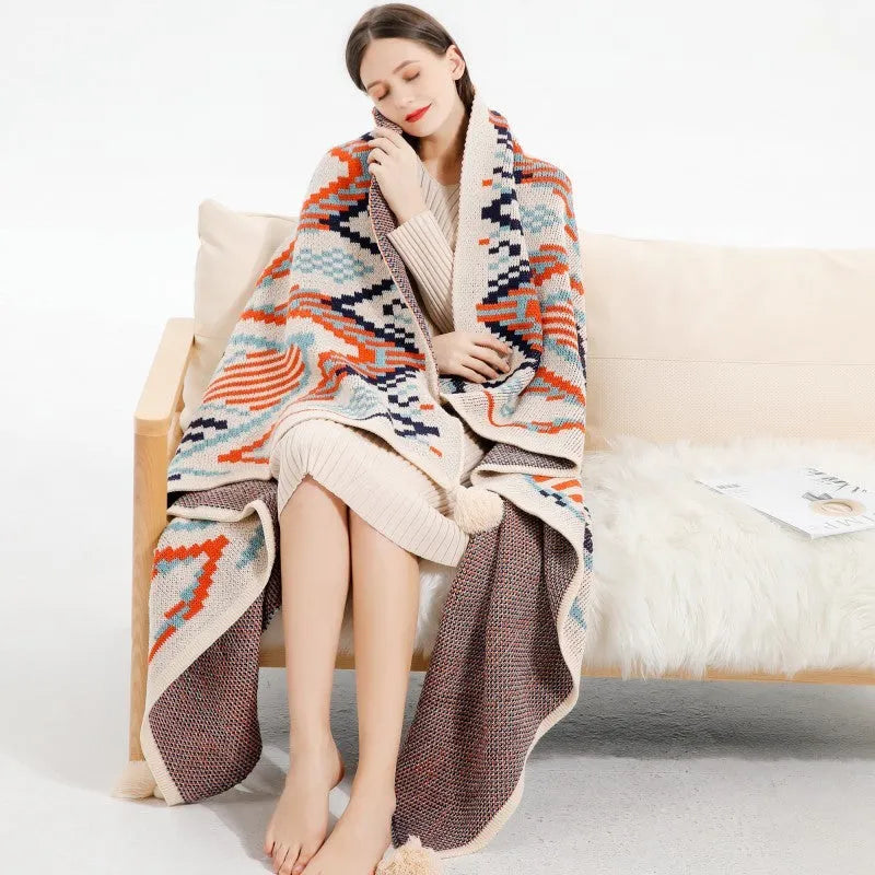 Bohemian-style acrylic sofa blanket with tassel trim shown in a beige and orange colour.