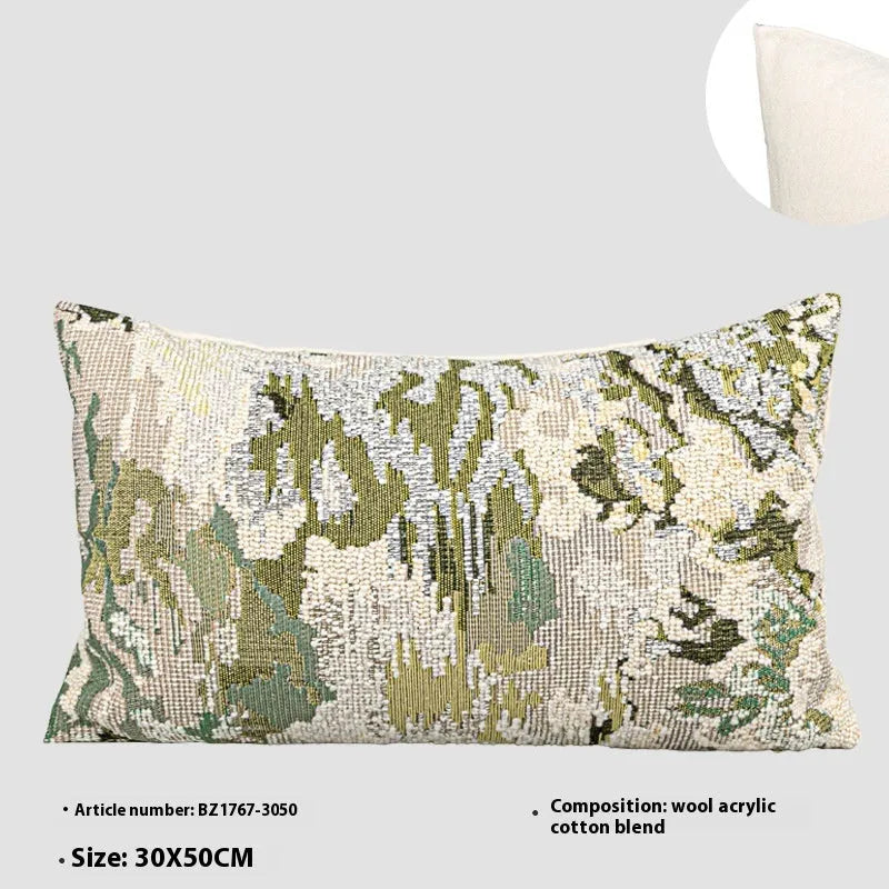 Antique green square pillow with abstract spring flowers pattern on a grey sofa.