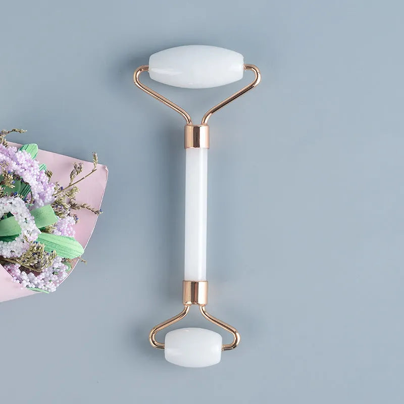 Natural white jade double-headed facial roller and gua sha board set on a plain background.
