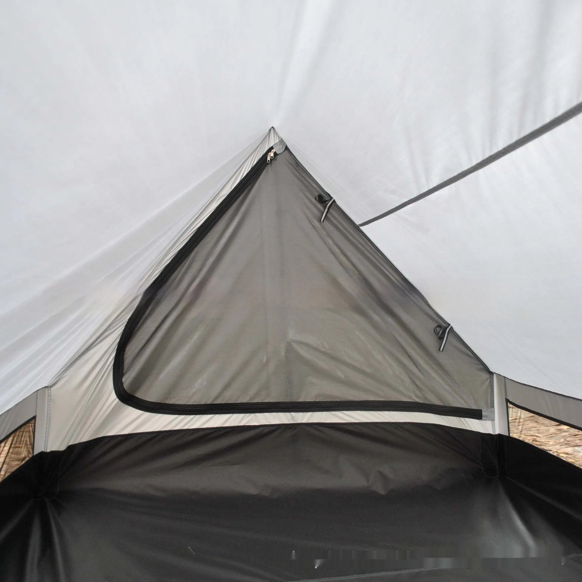 Brown A-line cabin tent pitched using hiking poles with aluminium ground nails and fluorescent wind ropes