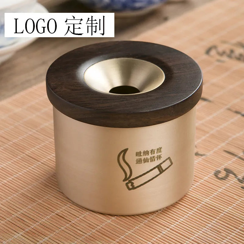 Brass ashtray with wooden lid in blackwood or rosewood finish, 6 cm diameter, on a table.