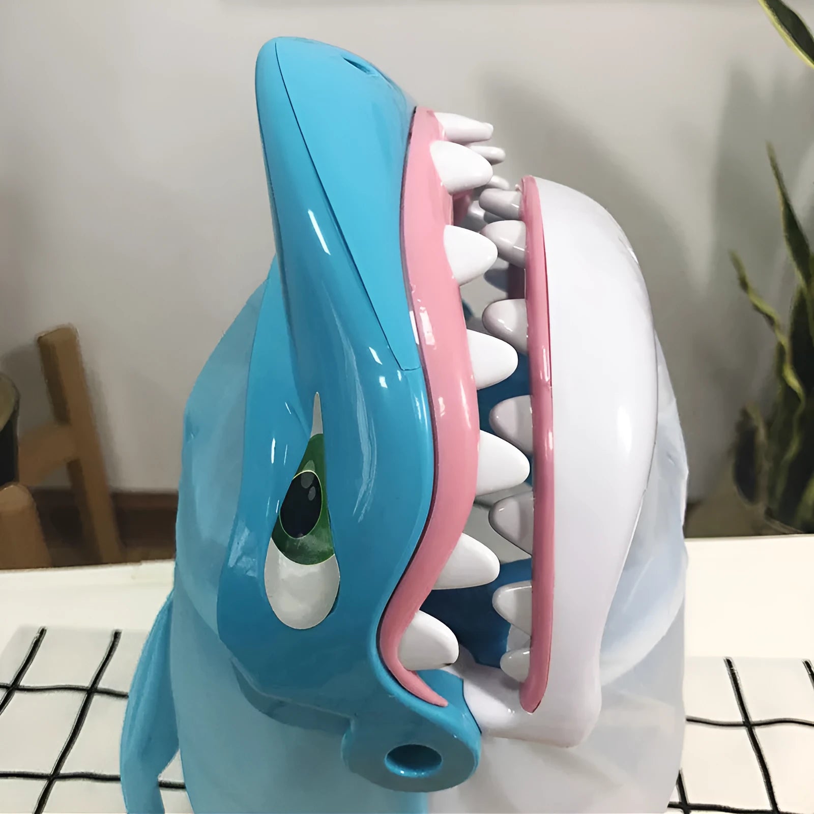Great white shark tricky toy with small plastic fish inserted in its mouth on a tabletop