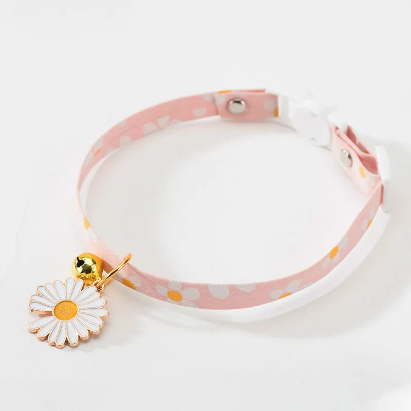 Adjustable green pet collar with a metal bell and pink bow tie on a small dog.