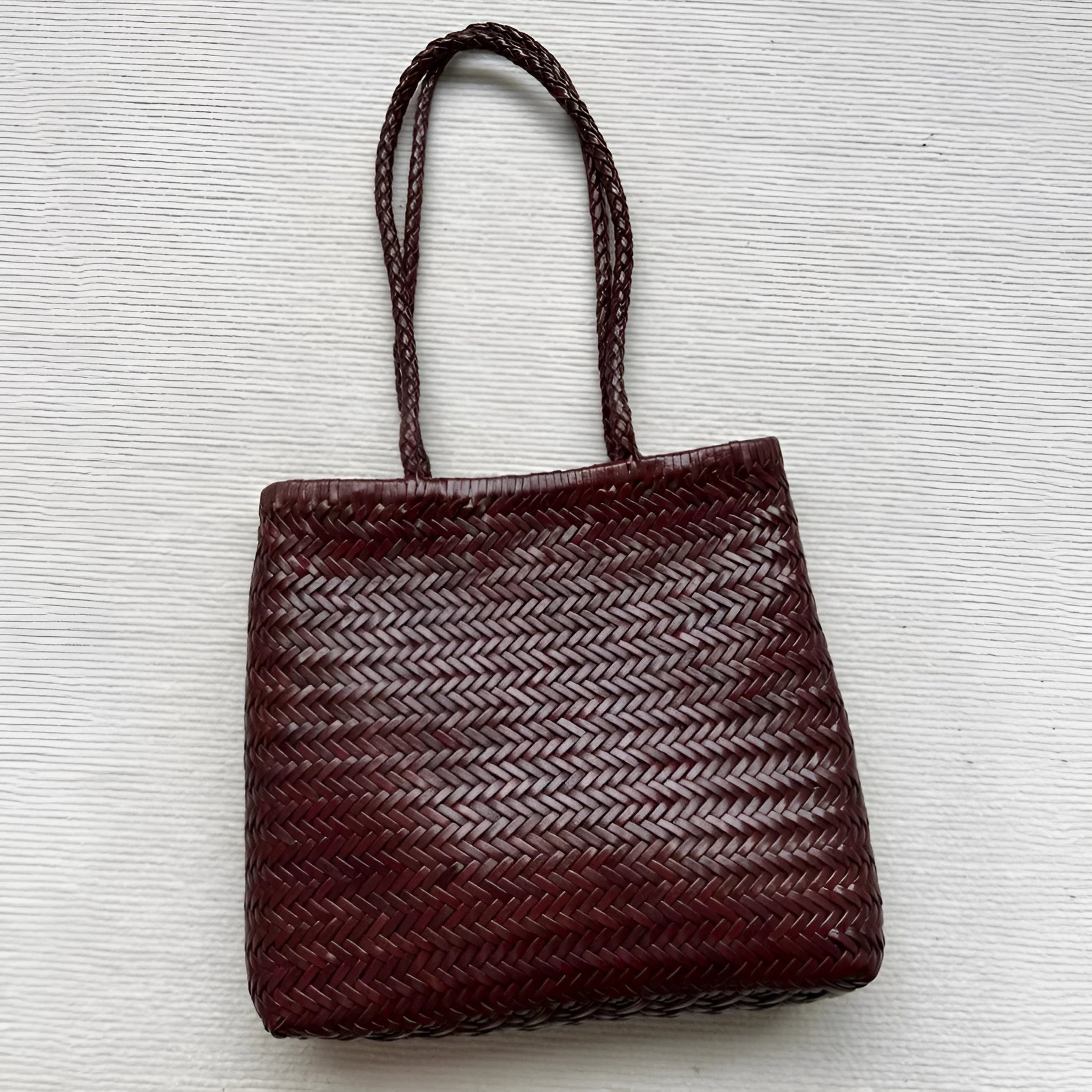 Brown woven leather tote bag with three-dimensional pockets and shoulder straps