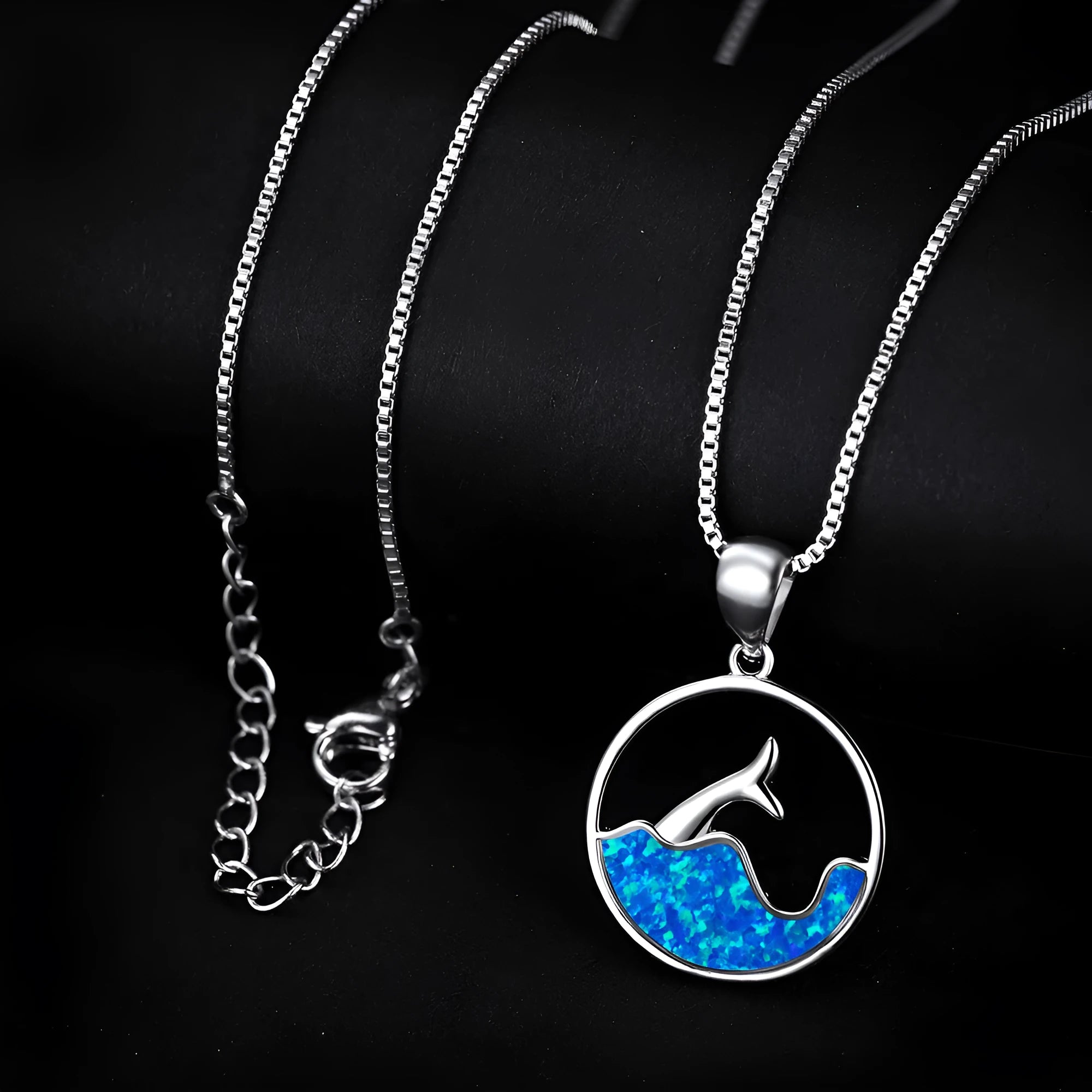 White gold electroplated sea fishtail necklace with a round blue opal pendant on a chain.