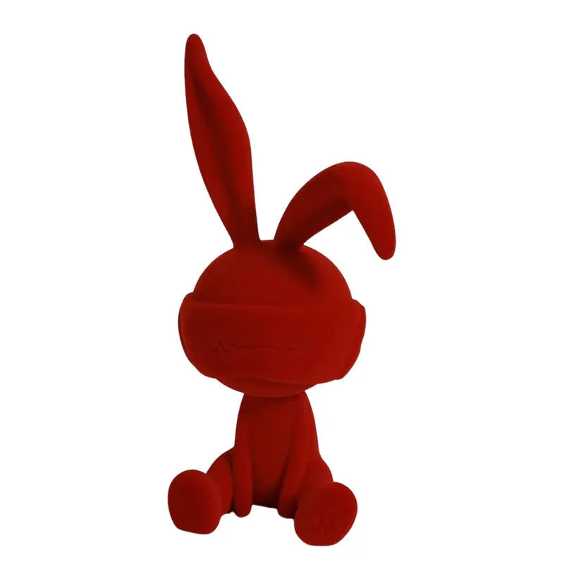 Small blue resin ornament of a rabbit wearing a blindfold on a wooden table.