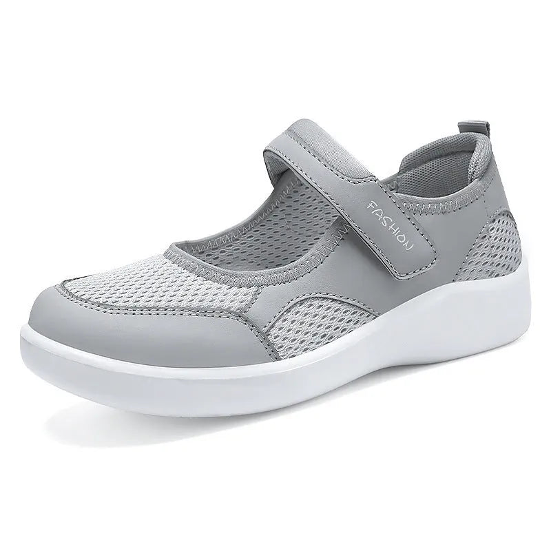 Women's grey breathable mesh slip-on shoe with Velcro strap, flat heel, and round toe.