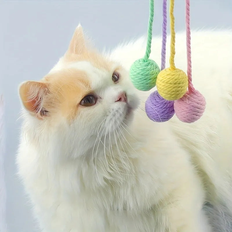 Green cat toy ball with attached rope and internal bell next to a pink one.