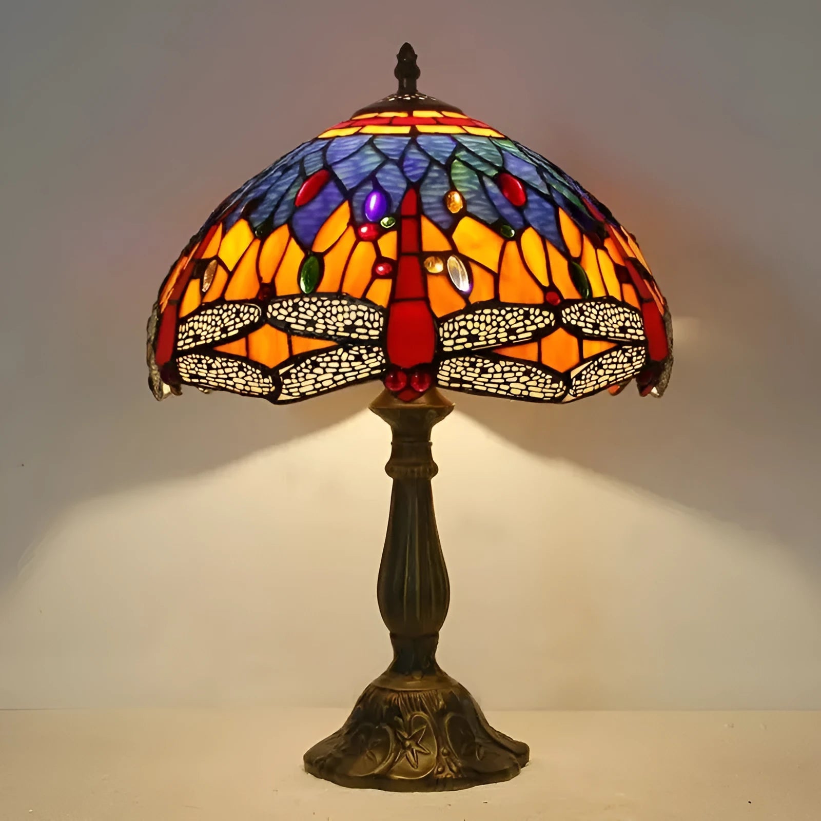 Tiffany style stone table lamp with blue dragonfly design on a bedside table.