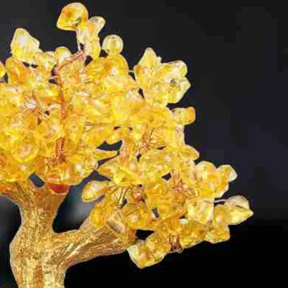 Citrine-coloured resin turtle money tree ornament on a neutral background.