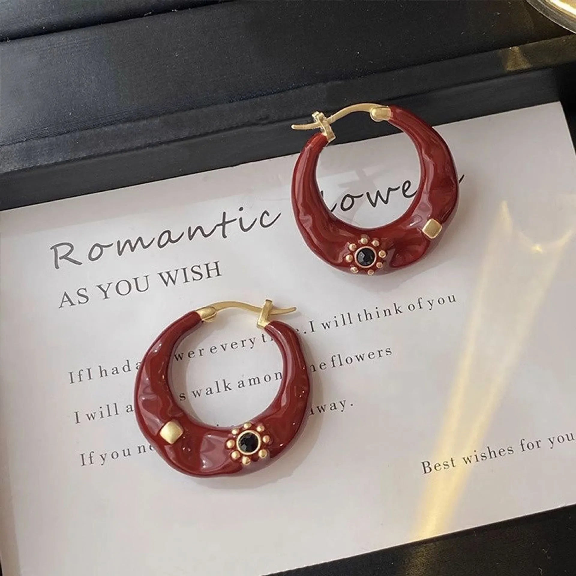 A pair of retro alloy ear studs with a dripping oil finish and black rhinestone detail.