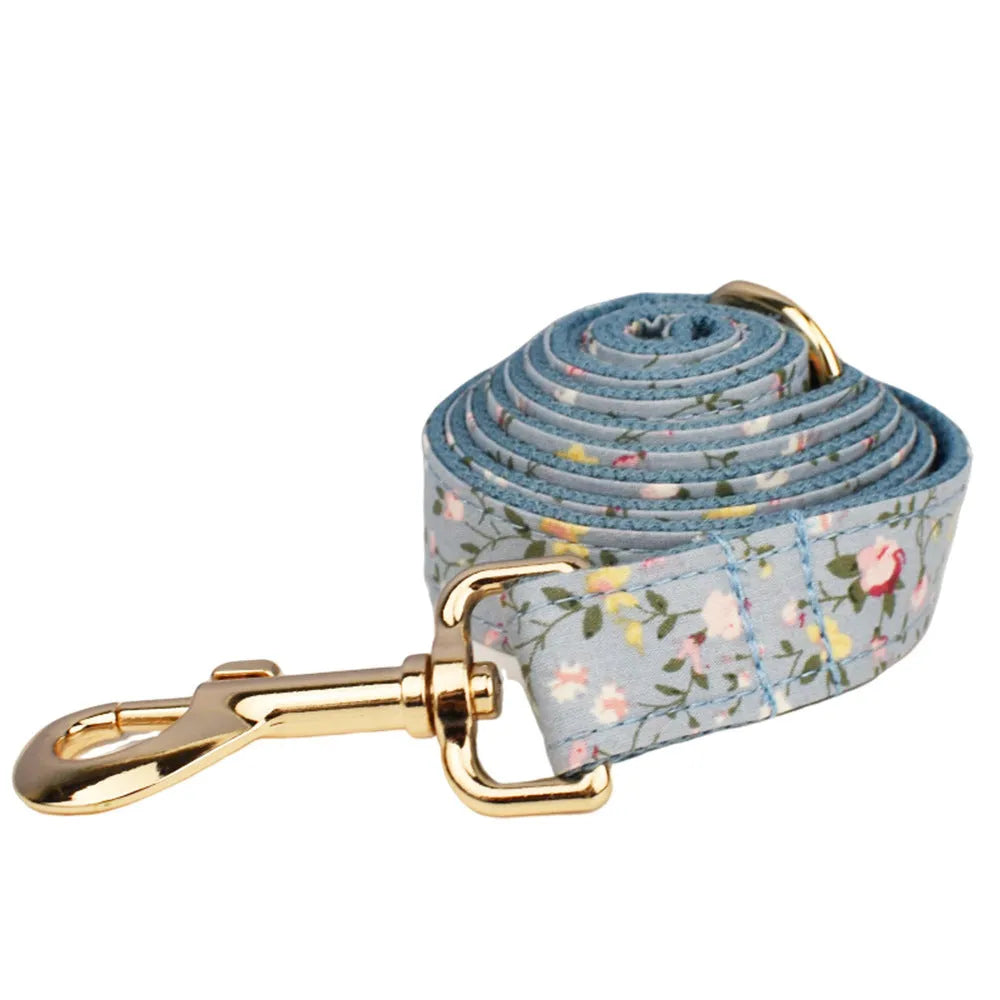 Blue floral pattern dog collar with matching leash, bow tie, vest and waste bag accessories on white background
