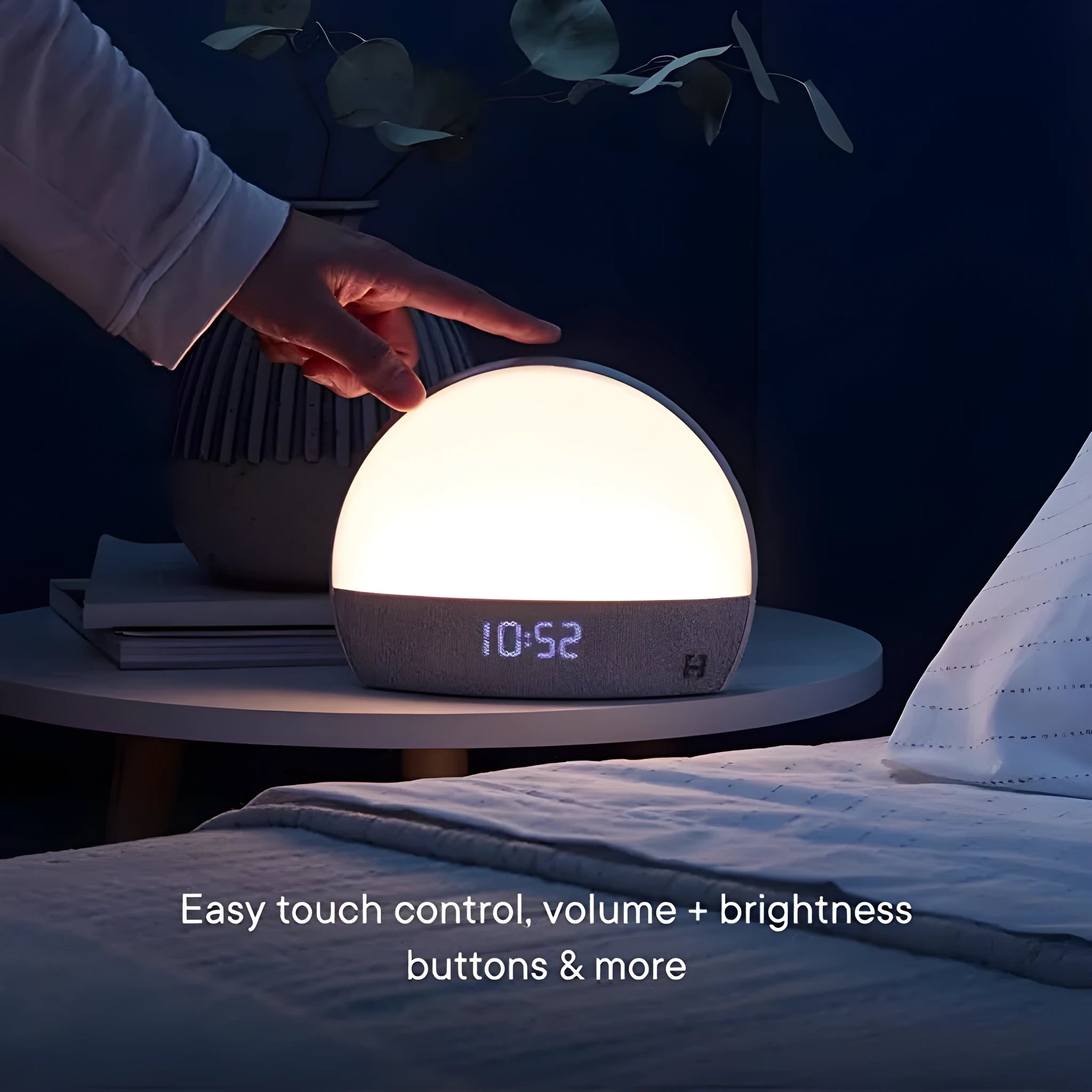 Hatch Restore smart clock in light grey with a night light and white noise machine on a bedside table