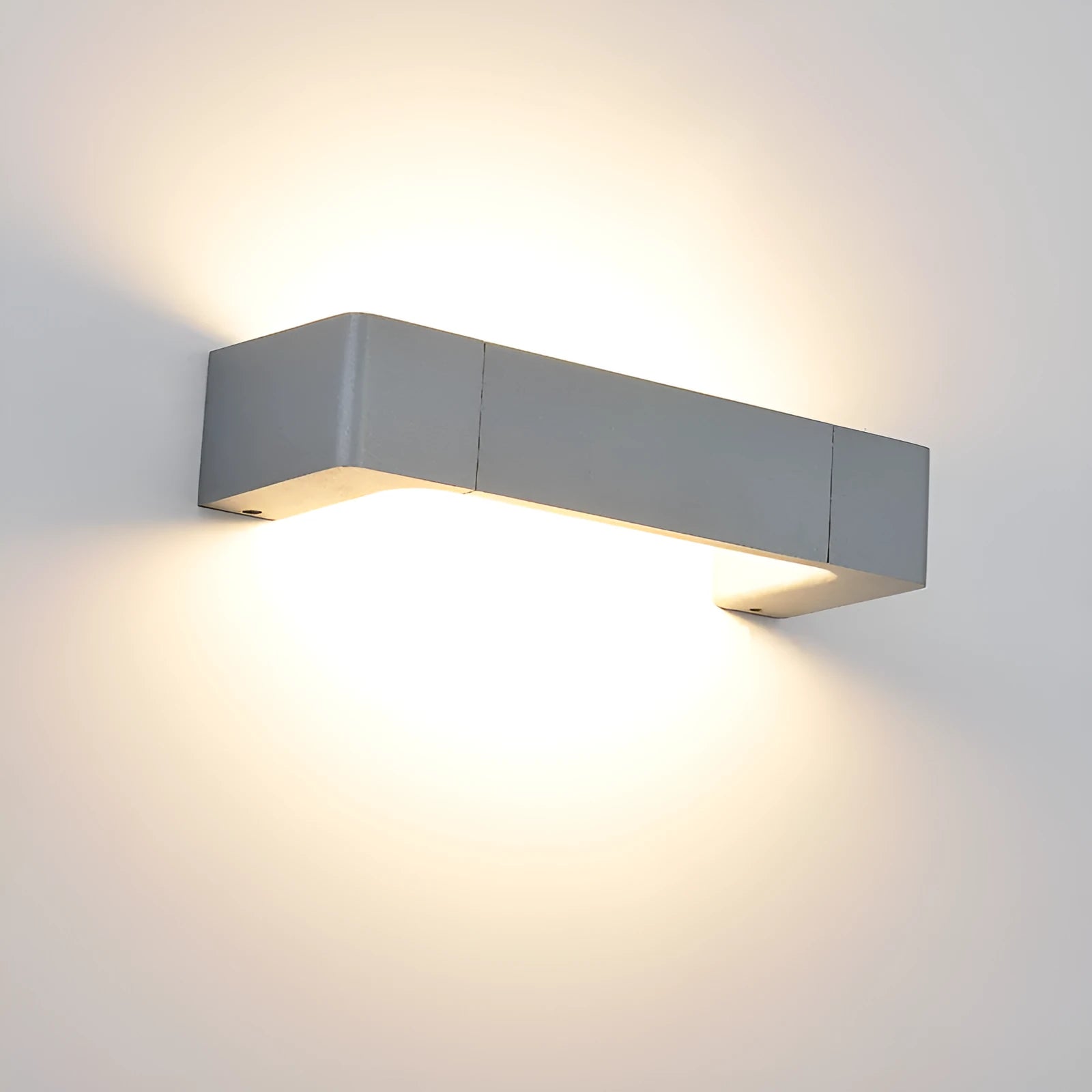 Modern minimalist wall lamp with aluminium shade in gold finish against a white wall