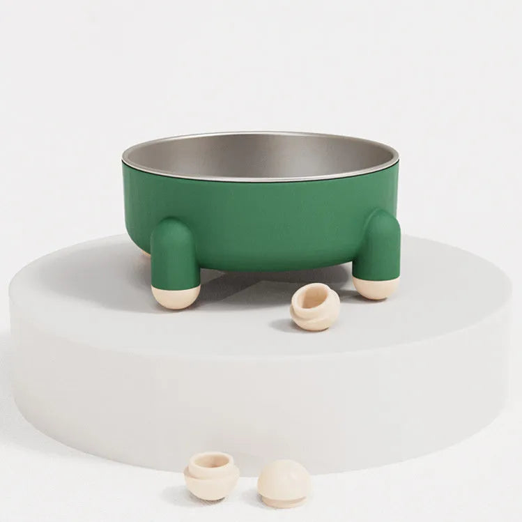 Green stainless steel pet bowl with a non-slip rubber ring and raised foot design on a wooden floor.