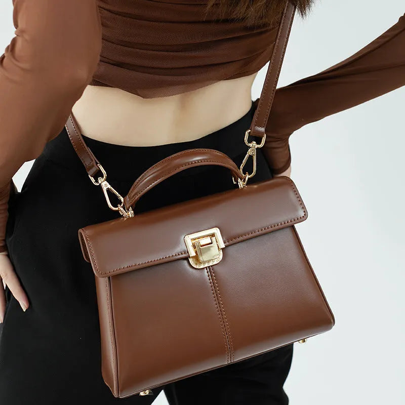 Women's black leather shoulder bag with vachette clasp showing organised interior compartments