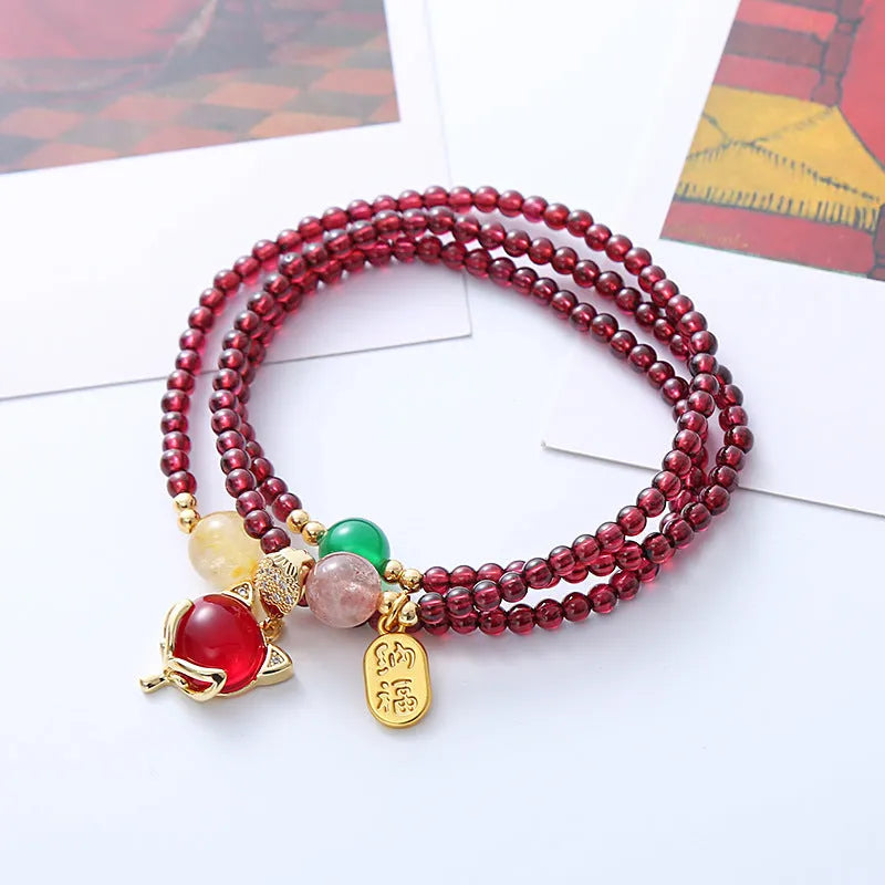Purplish red garnet bead bracelet with a silver fox charm and adjustable rope fastening.