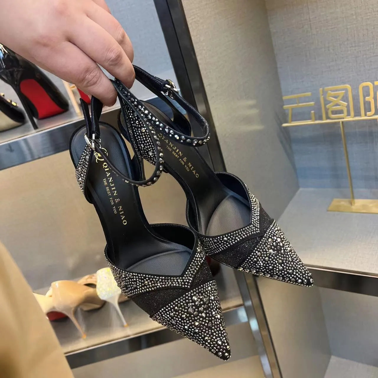 Women's black pointed toe high heels with a hollow stiletto heel and red sole, shown from the side.