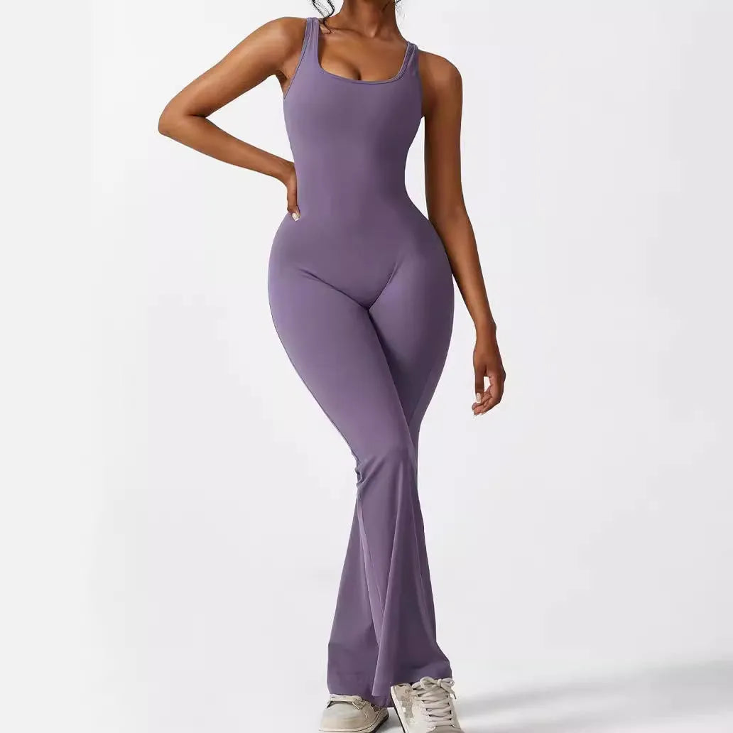 Woman wearing a sleeveless army green flare jumpsuit for yoga.