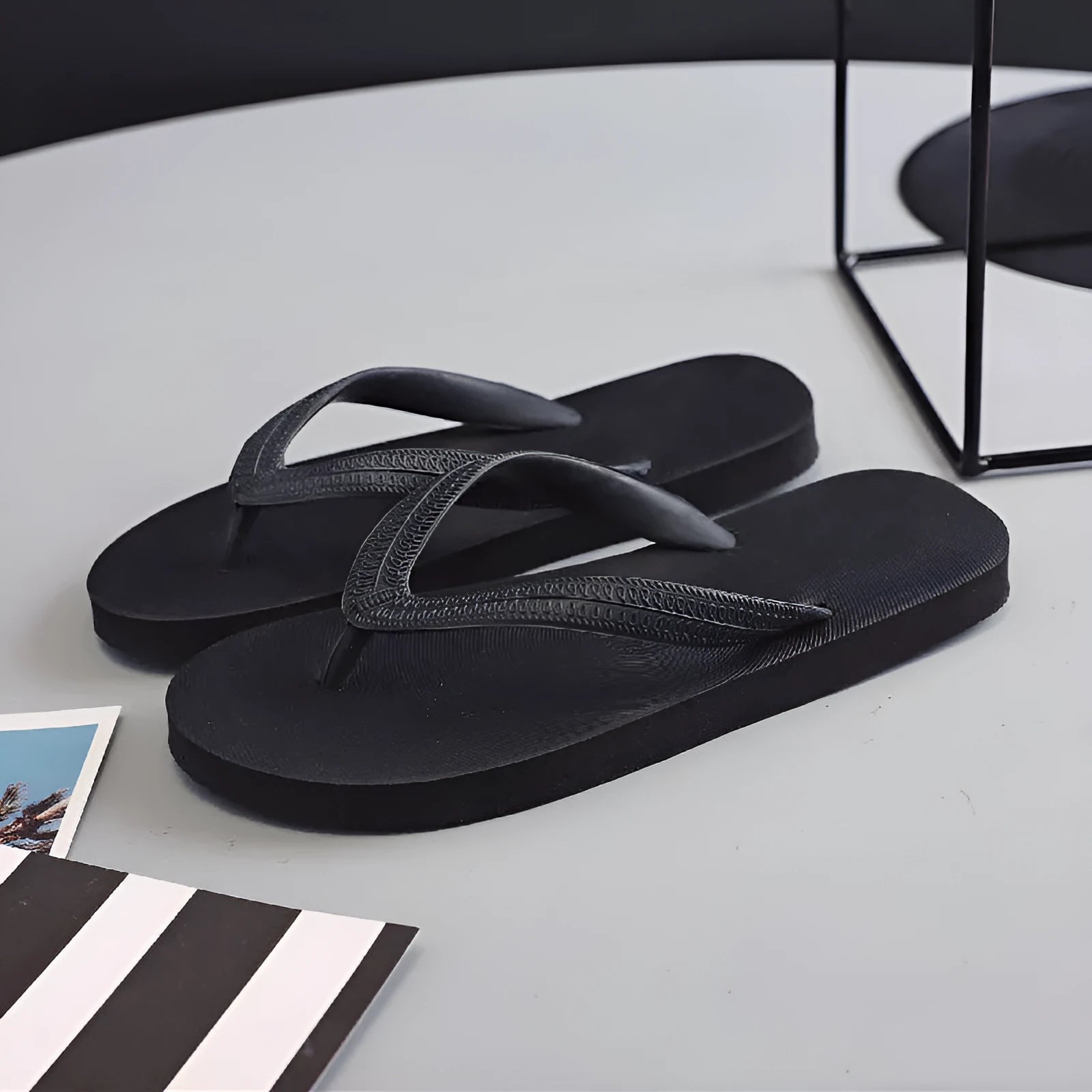 A pair of rubber flip-flops with a fish label on the strap, showcasing a non-slip patterned sole.