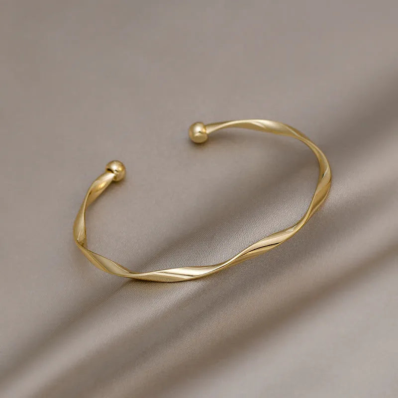 Gold alloy geometric twist bracelet with 6.2 cm inner ring diameter on white background