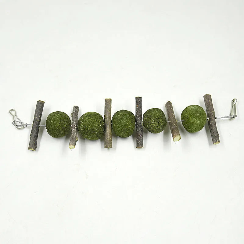 Set of five grass balls and six apple branch pet molar chew toys on a string, hanging against a plain background