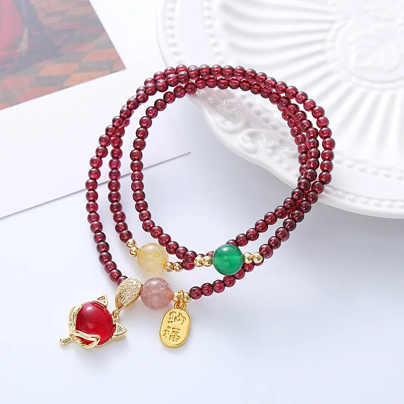 Purplish red garnet bead bracelet with a silver fox charm and adjustable rope fastening.