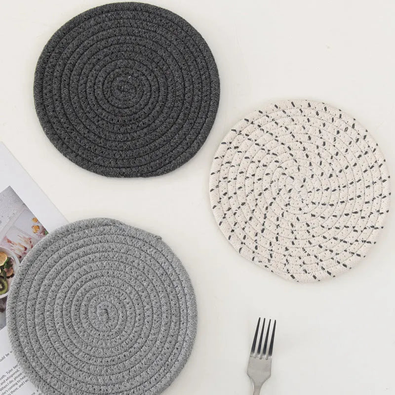 Three round blue cotton cord coaster placemats on a wooden table.