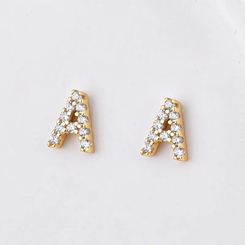 A pair of brass stud earrings featuring a single gold-plated English alphabet letter.