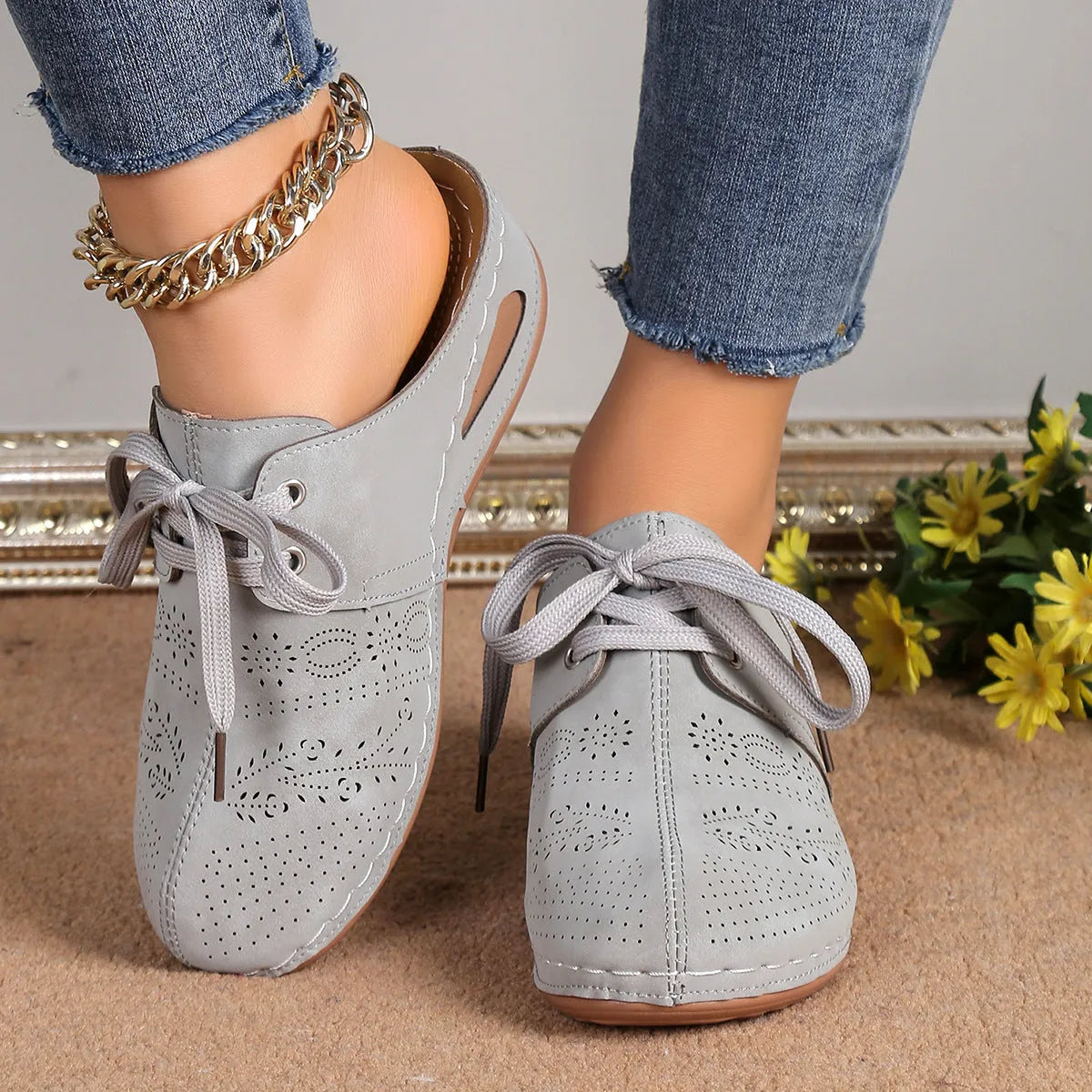 Women's lace-up suede wedge slippers with a hollow-out design, shown in a light colour on a foot.