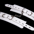 White PU sponge bondage set showing handcuffs, footcuffs, and a neck scarf arranged together.