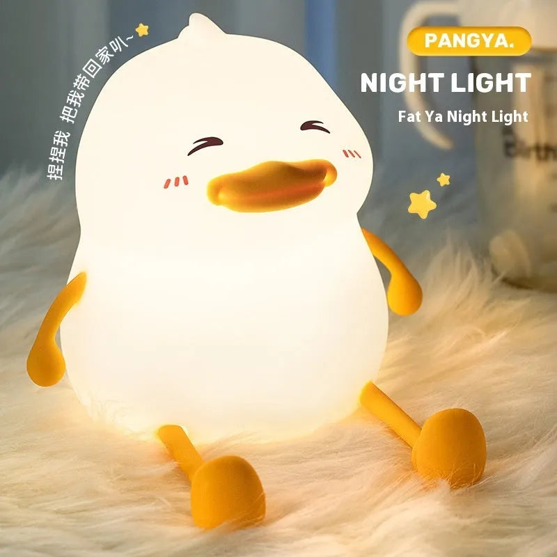 Chubby white silicone night lamp on a desk holding a mobile phone, showing soft LED glow.