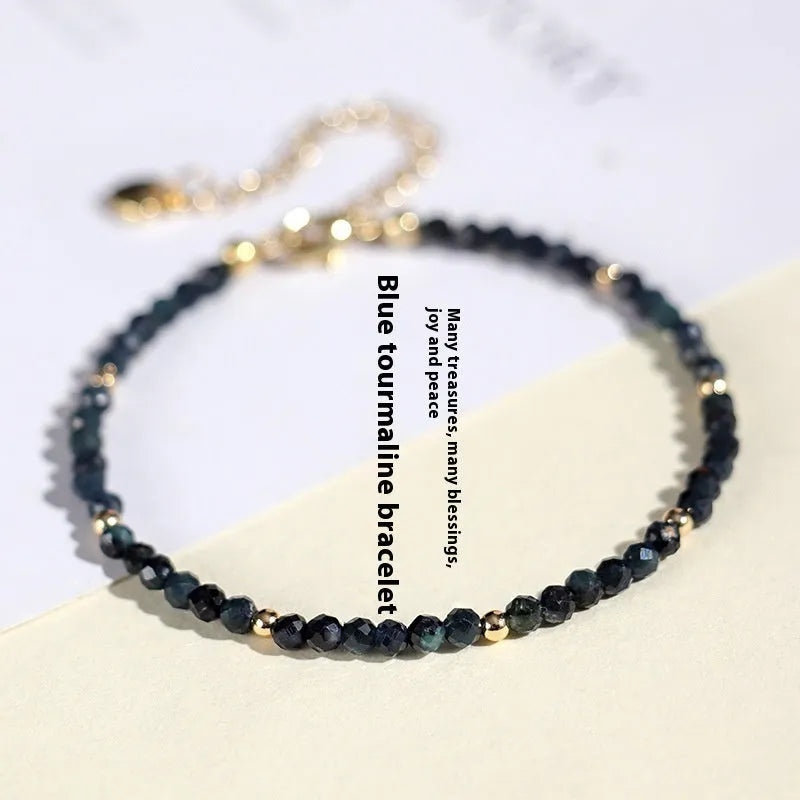 Close-up of a 3mm blue tourmaline cut bead spacer bracelet on a wrist.