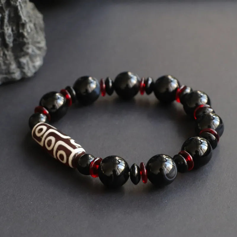 Close-up of a hand-woven black agate dzi bead bracelet with 11mm geometric beads on a wrist.